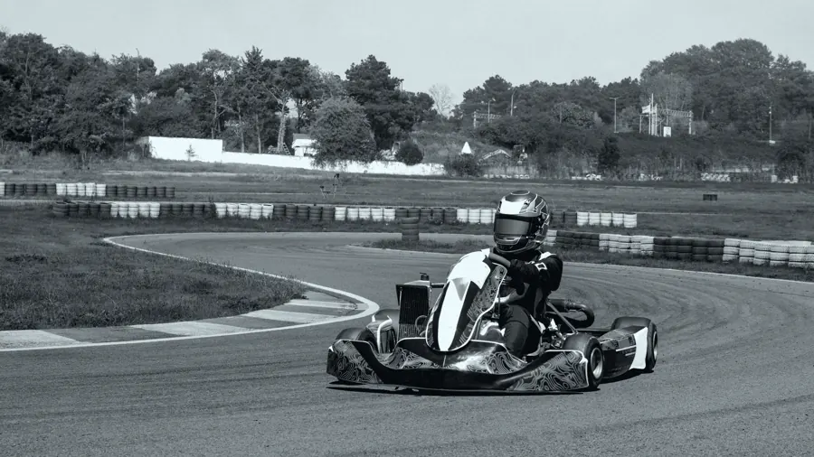 Kart contornando uma curva de asfalto, piloto de capacete inclinado para dentro.