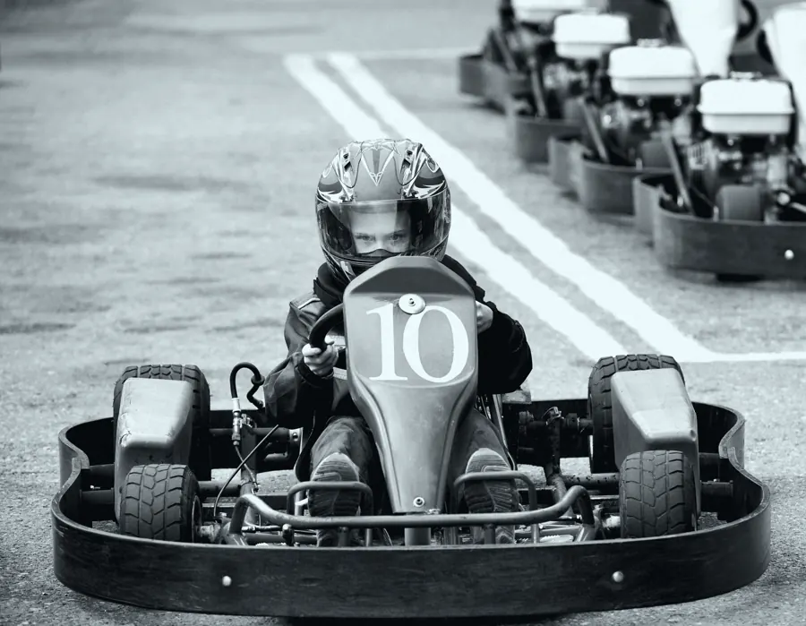 Criança de capacete pilotando um kart de número 10, vista de frente.